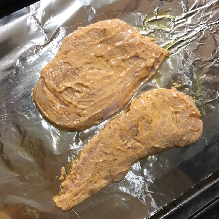 harissa sauce slathered chicken breasts on cooking sheet