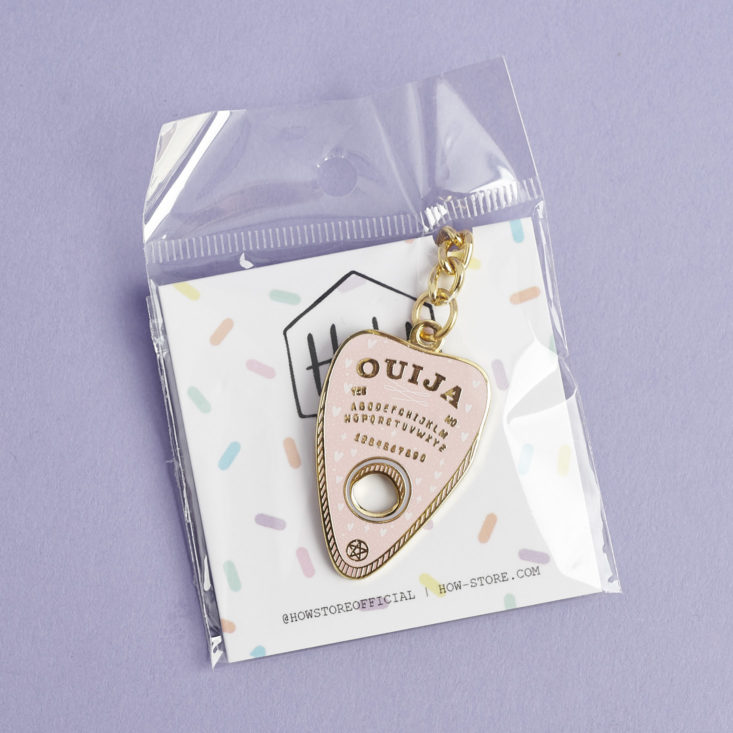 pink and gold ouija board keychain in package
