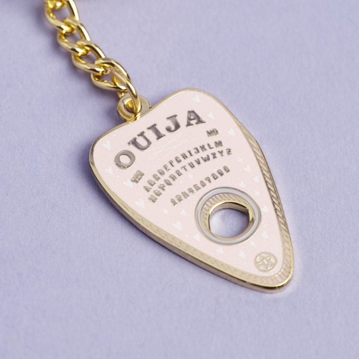 close up of pink and gold ouija board keychain