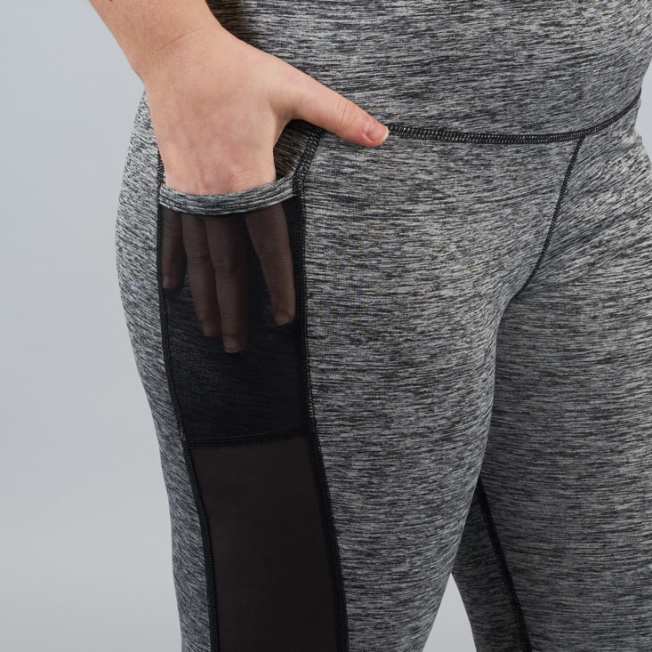 hand in a sheer pocket panel of gray leggings