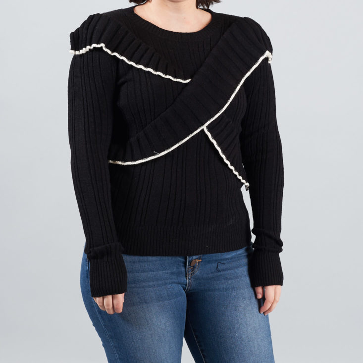 black sweater with ruffles and white trim
