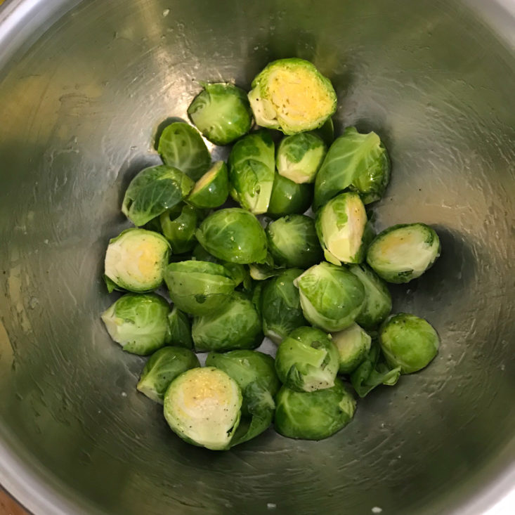 halves brussels sprouts in bowl with olive oil, salt, and pepper
