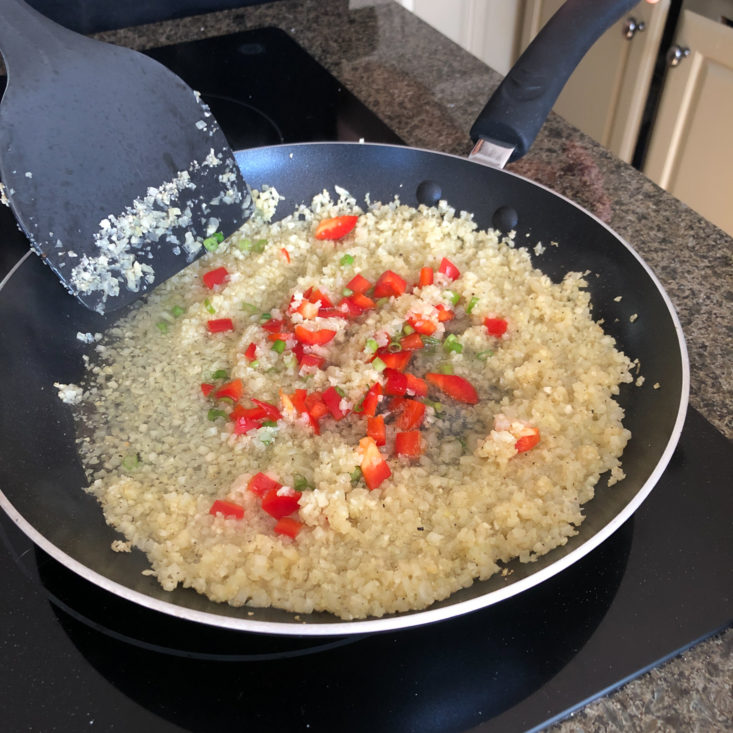 adding veggies to cauliflower rice