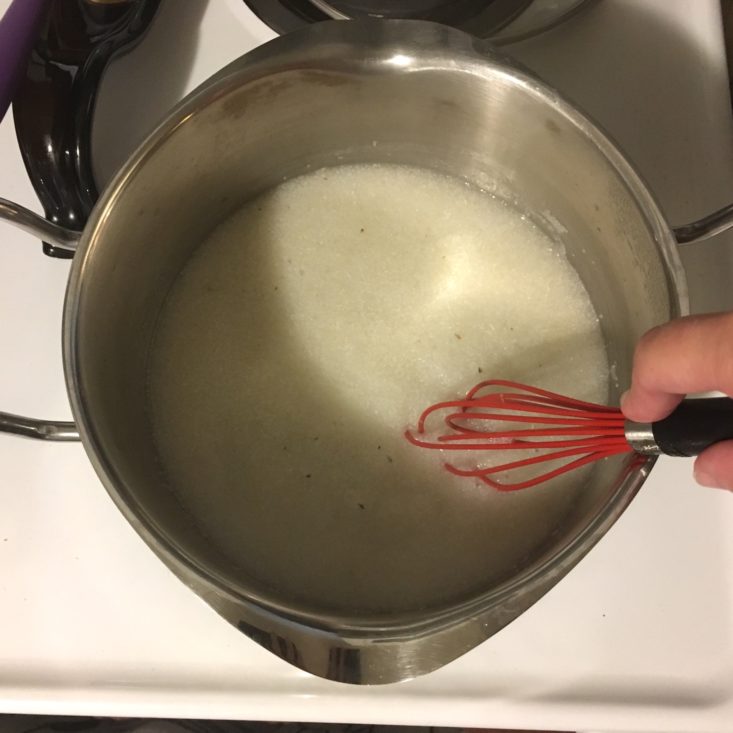 grits being whisked together in a medium-sized pot over high heat