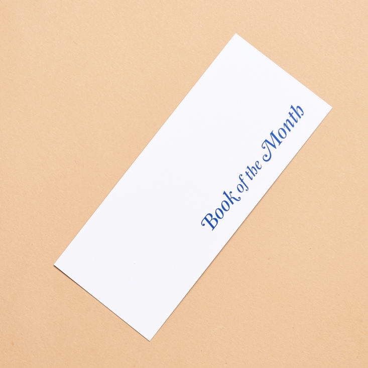 white back of bookmark with book of the month logo in blue
